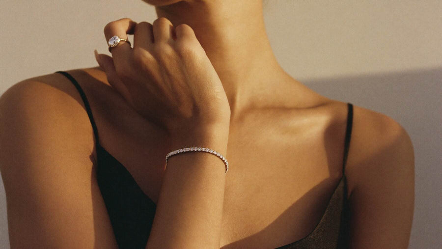 A woman in a black silk slip at golden hour, a diamond line bracelet on her wrist