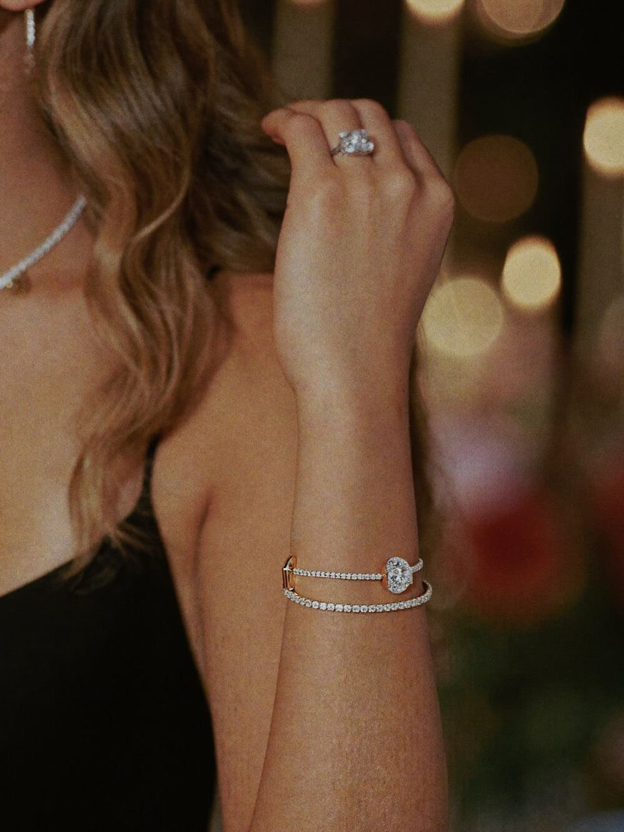 A woman in a black dress raising her wrist in candlelight, diamonds catching the light