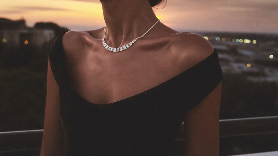 On a terrace at dusk, a woman wears an emerald-cut diamond necklace
